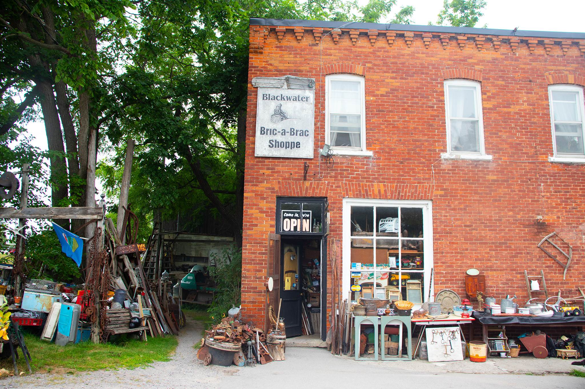Image of an antique store with knick knacks on tables and in piles along the front of the shop