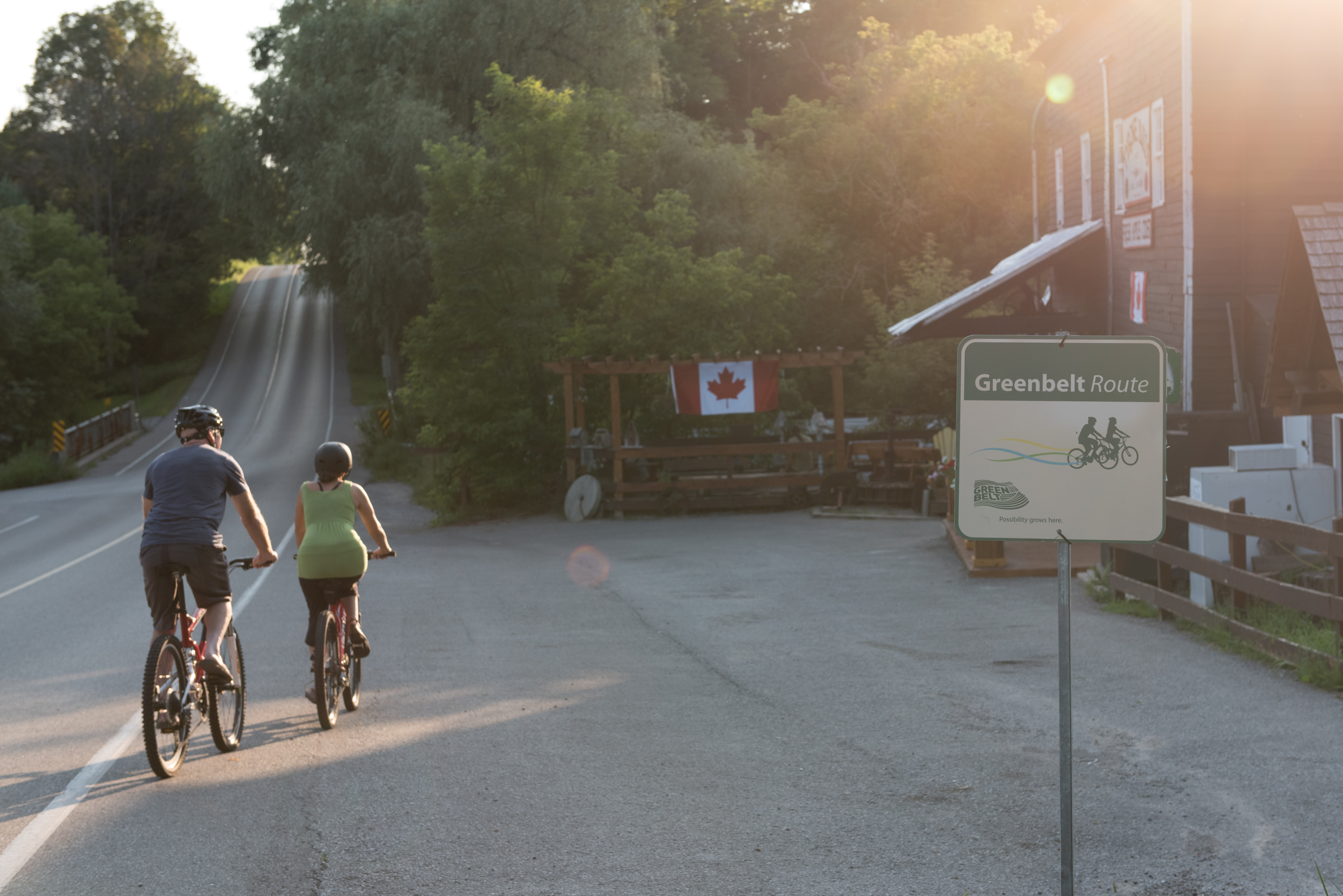 Cyclists arrive at Tyrone Mills in Clarington Two cyclists riding their bikes and arriving at Tyrone Mills in Clarington. There is a Greenbelt Cycling route sign,