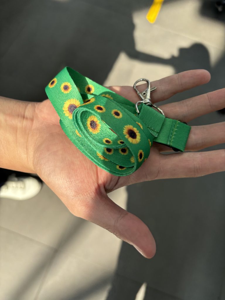 A hand holding a sunflower lanyard
