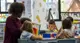early childhood educator sitting at table full of children in a child care centre