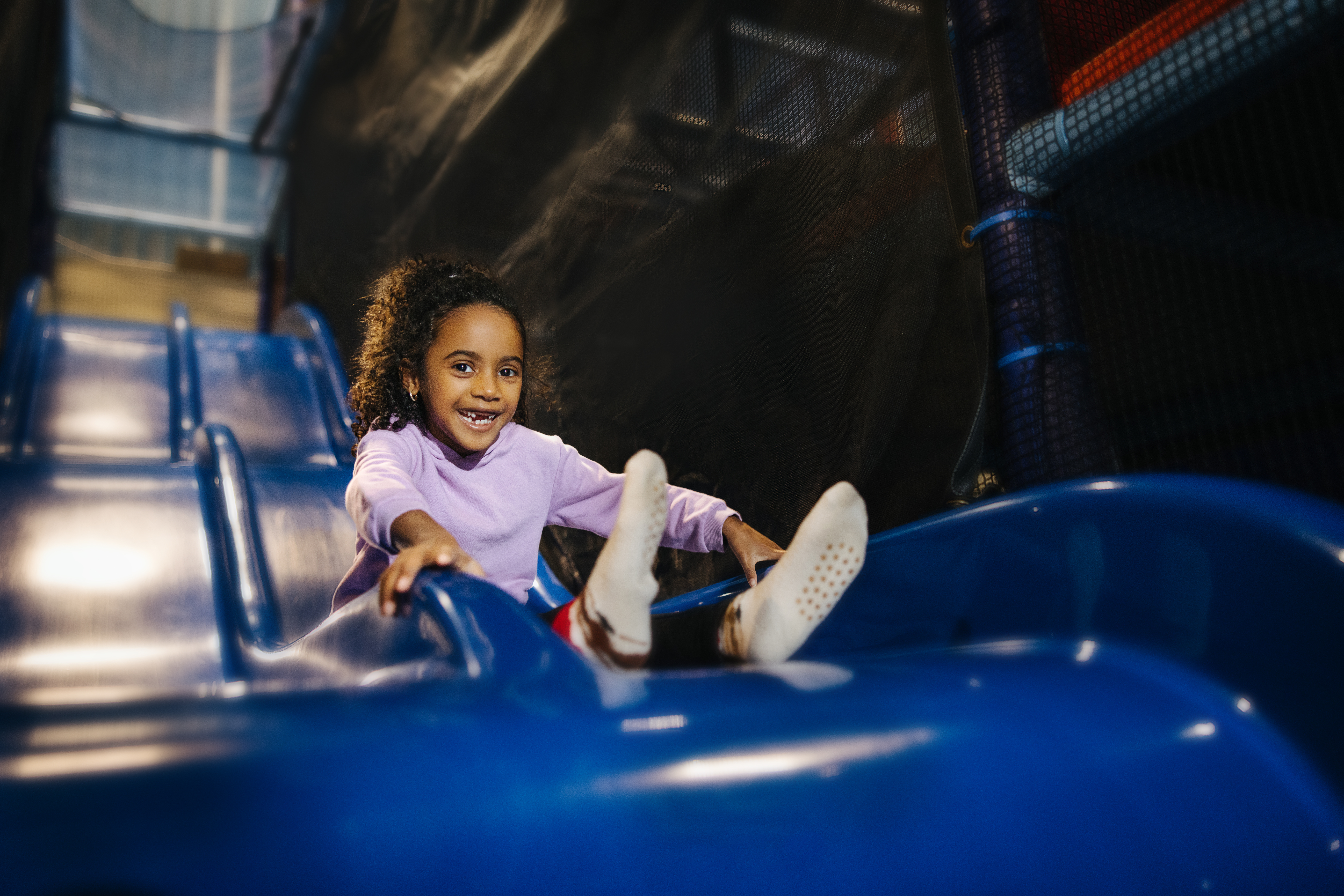 Little girl at Joey's World Little girl sliding down a blue slide