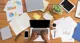 Hands typing on laptop surrounded by paperwork