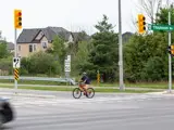 Cyclist riding red bicycle through crossride at signalized intersection