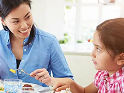 Mother and daughter eating at the table.
