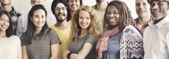 A diverse group of people standing close together, smiling at the camera.
