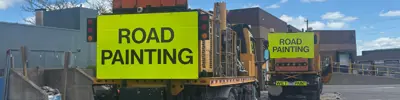 Two road painting trucks with Road Painting signs on the back.