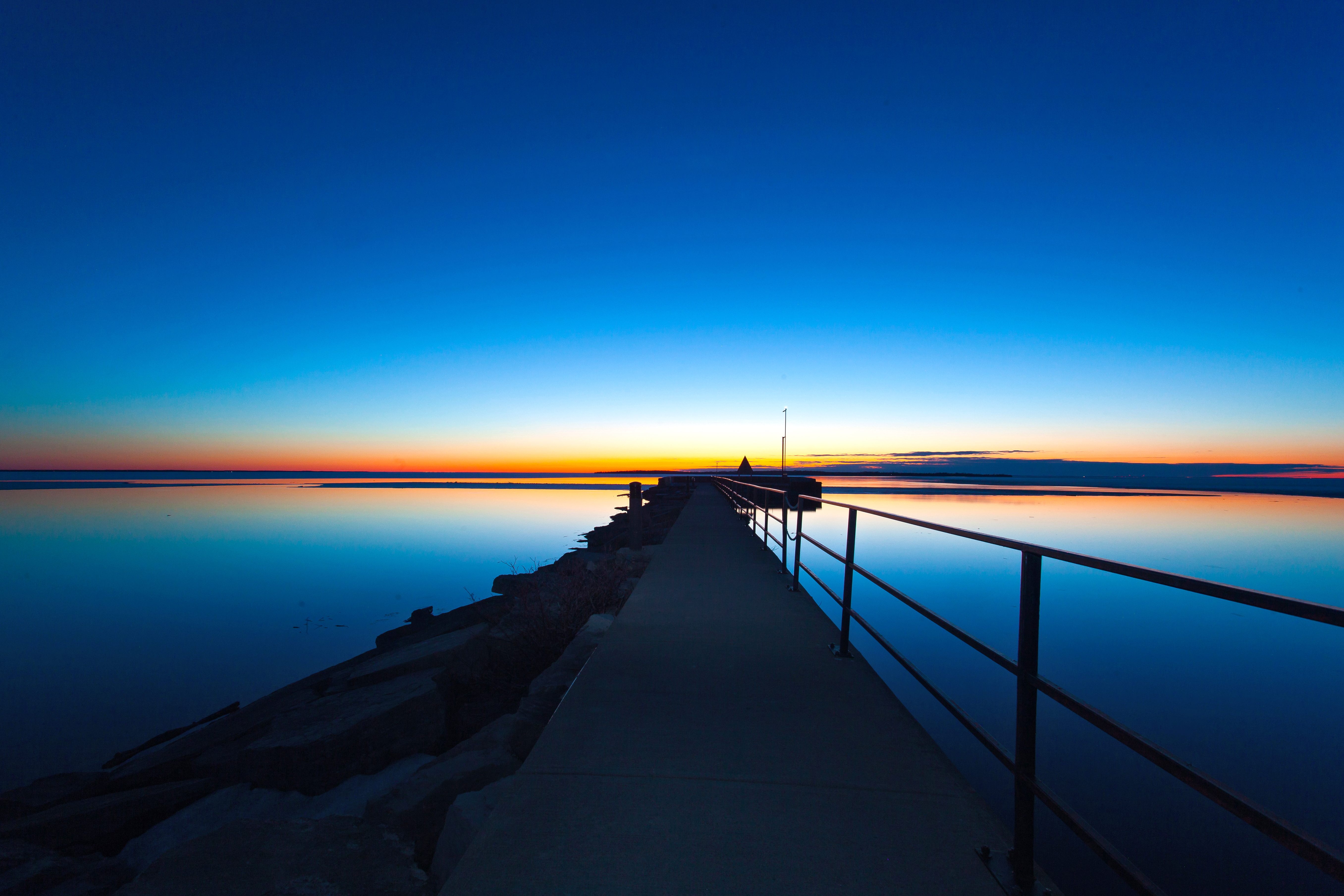 Sunset on Lake Simcoe at the Beaverton Harbour Photo taken on the pier during sunset at the Beaverton Harbour. The water is flat on Lake Simcoe and the sky features vibrant shades of blue, red and orange.